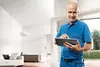 Ein Handwerker in blauer Kleidung bedient ein Tablet in einem modernen Raum.