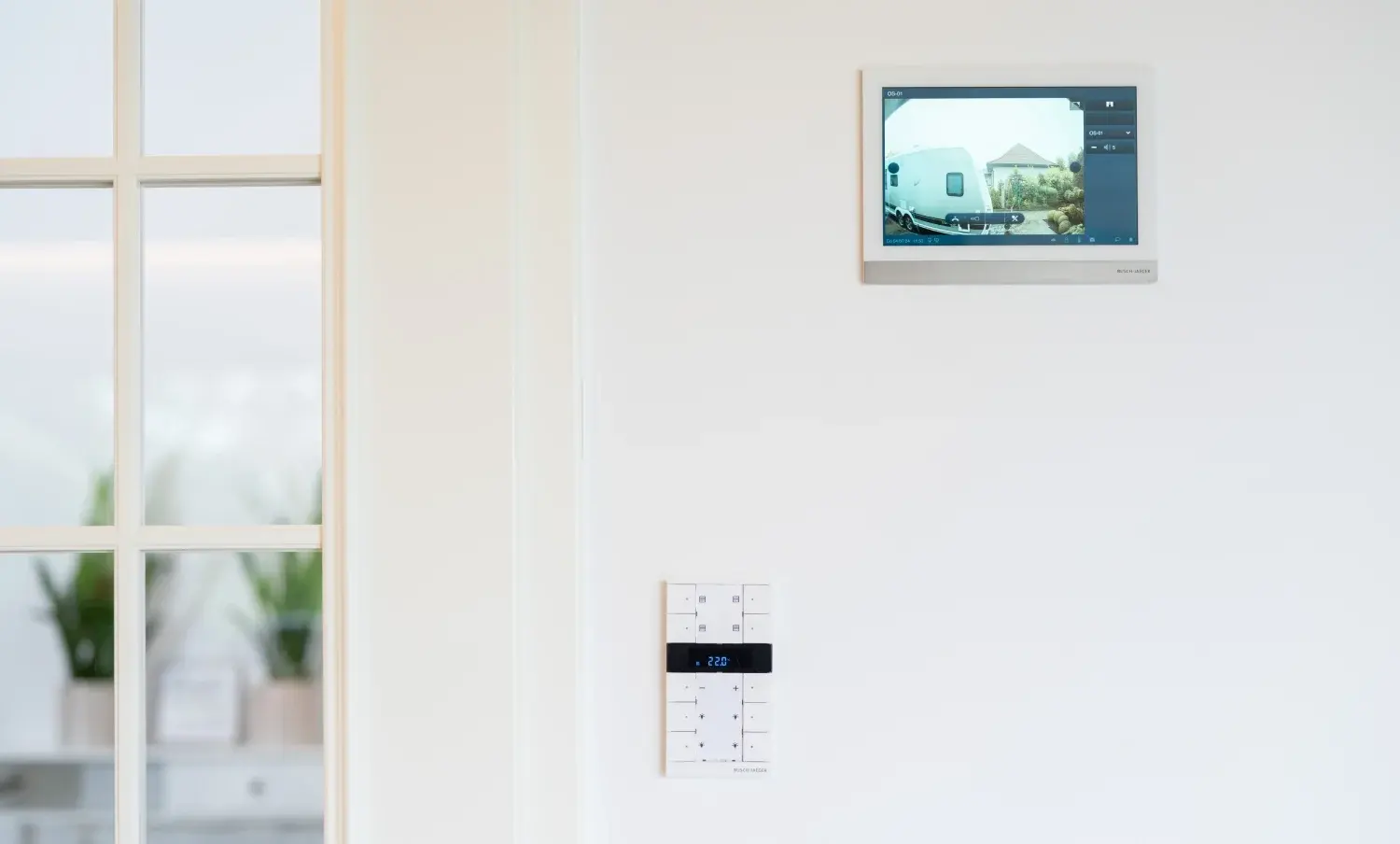 Deckenmonitor mit Kameraansicht und Bedienelementen an der Wand für smarte Heimsteuerung.