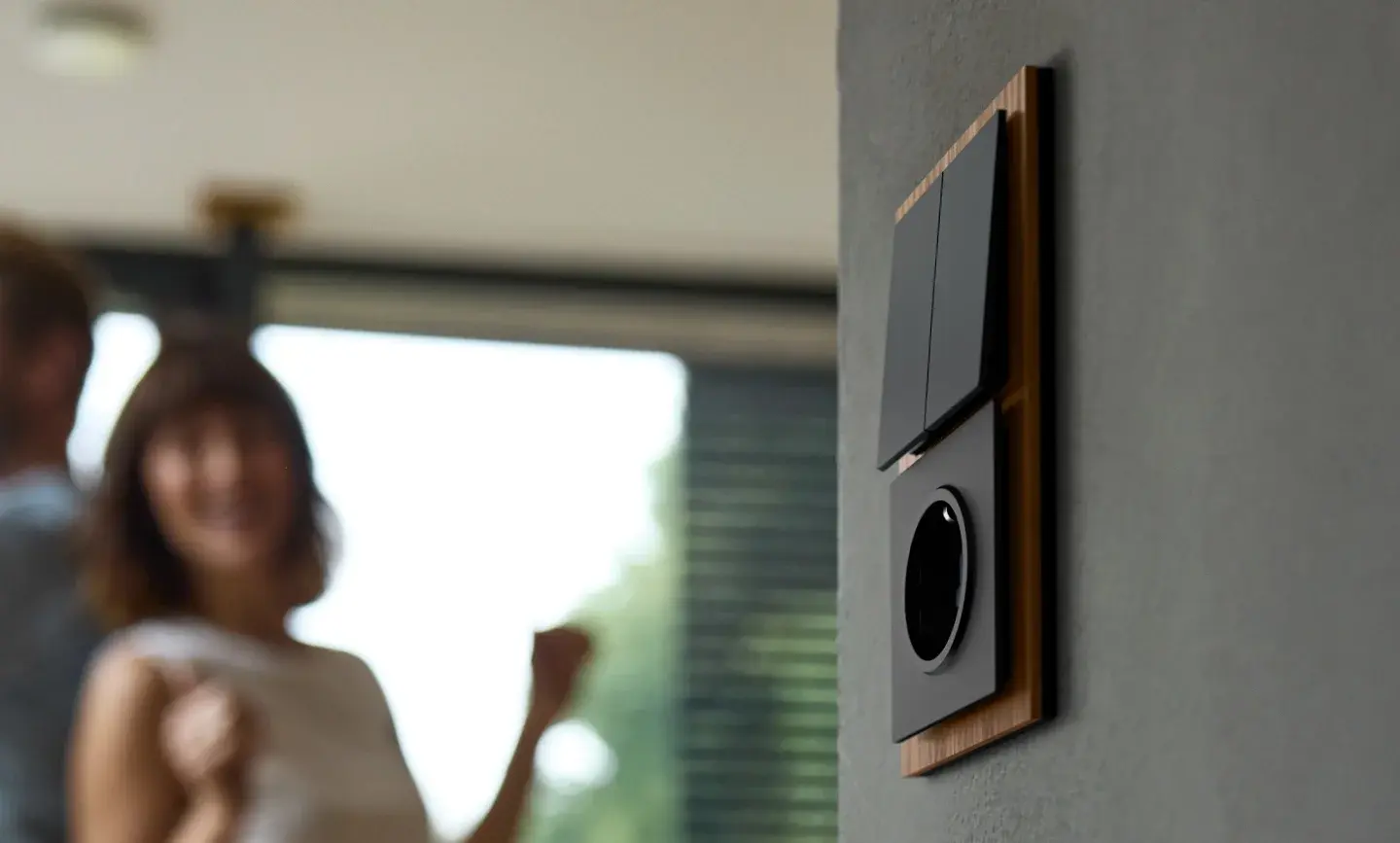 Moderne schakelaar op de muur en echtpaar op de achtergrond