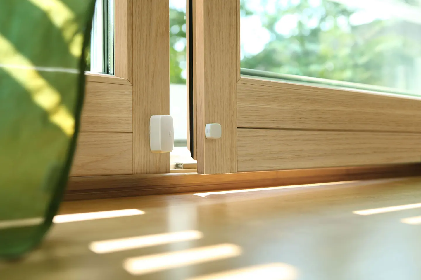 Zwei Fenster mit Holzrahmen, die leicht geöffnet sind, und einem Sensor an der oberen Kante.